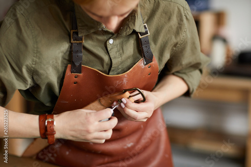 Mid section portrait of woman artisan making leather belt in leatherworking shop , copy space