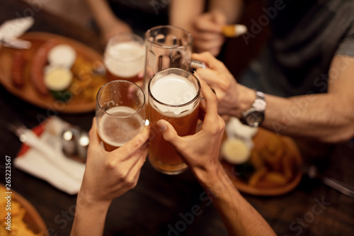 Close up of friends toasting with beer and having fun in a pub. Fototapet