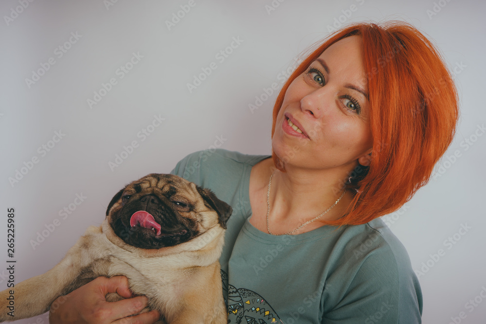 Beautiful woman holding cute pug puppy in her arms, on white background. The concept of friendship between man and dog. Beautiful woman holding cute pug puppy in her arms, on white background. The concept of friendship between man and dog.
