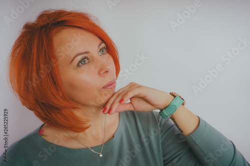 Young woman with red hair on white background. Portrait of a young attractive woman with a fashionable hairstyle.