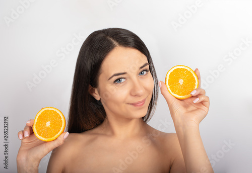 beautiful brunette girl, blue eyes, in her hand an orange, white background, close-up