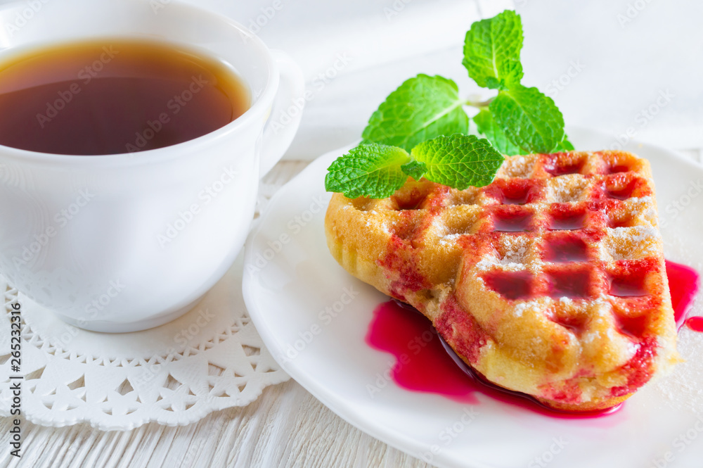 Homemade waffle and a cup of tea on a white wooden table. Homemade waffle and a cup of tea on a white wooden table.