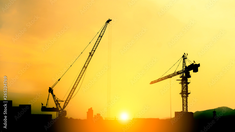 silhouette wear a helmet at construction site with crane background and sunset