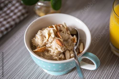 Bowl of homemade oatmeal porridge with almonds and orange juice