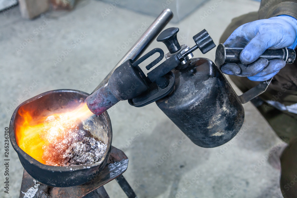 Professional male worker using a gas torch to melt lead metal