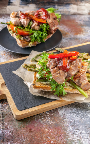 Mediterranean Kitchen. Vertical shot. Grilled turkey meat on a traditional chabbata with sweet peppers, tomatoes and herbs on a cutting board.