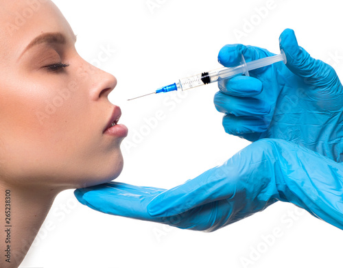 cropped image of doctor's hands in latex gloves giving injection with syringe to woman's lips isolated on white