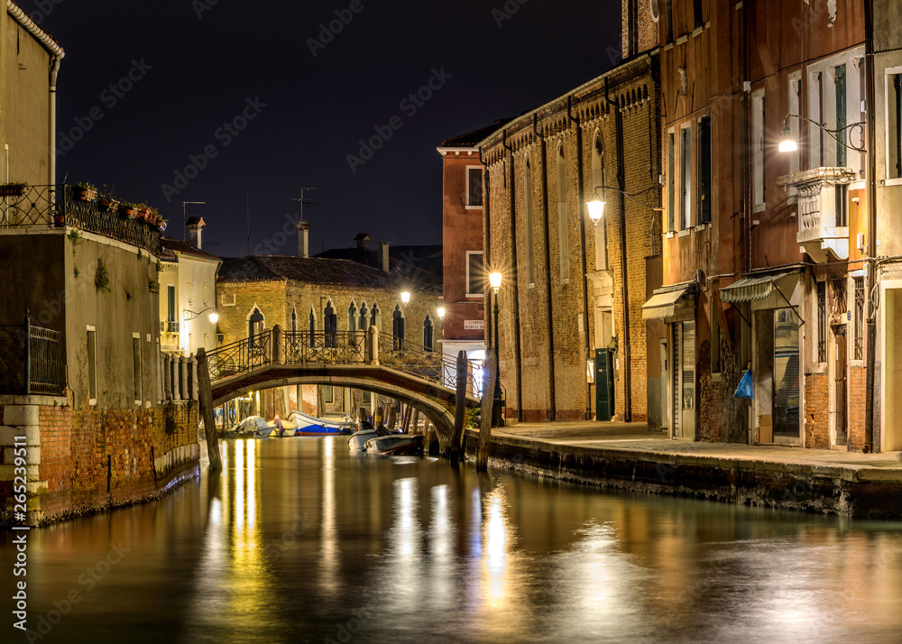 Night at Murano - A night view of a small old brick bridge, Ponte San Pietro Martire, crossing over a narrow waterway, Rio dei Vetrai, at the center of Murano Islands. Near Venice, Veneto, Italy.