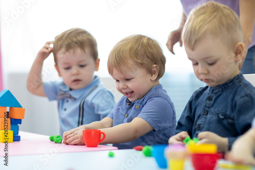 Nursery kids playing with play clay at kindergarten or playschool