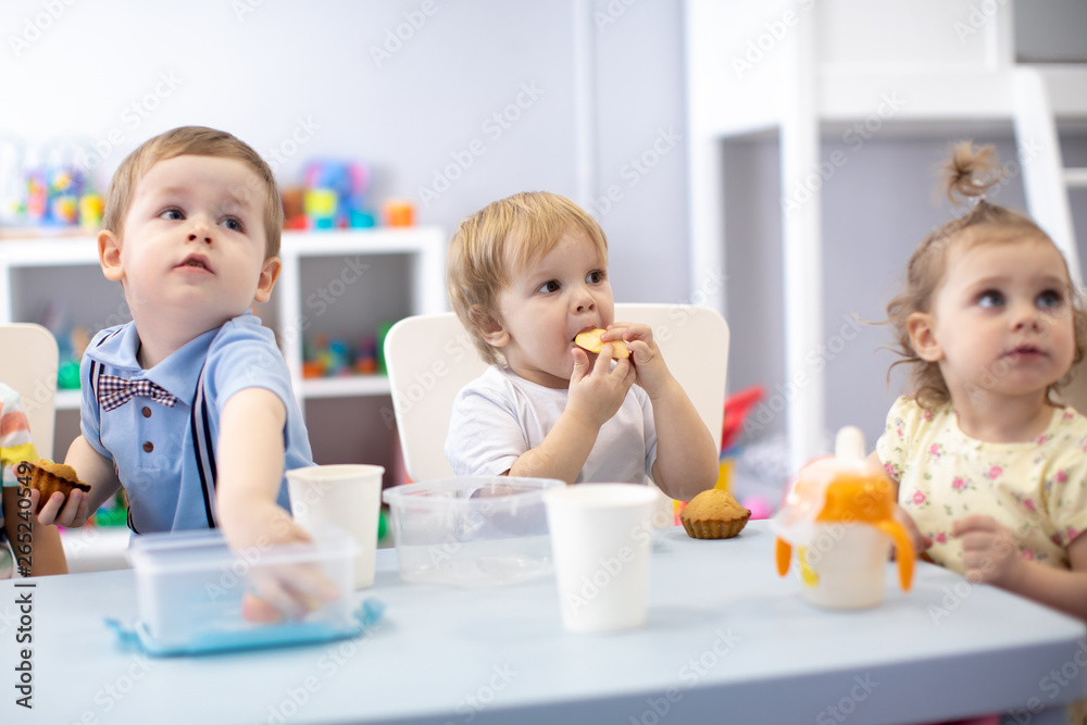 babies children eating healthy food in nursery or kindergarten