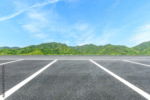 Parking lot pavement and green mountains natural landscape under the blue sky
