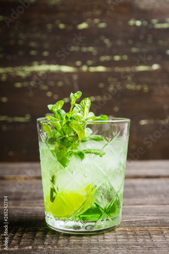 Summer old fashioned beverage with melon liqueur and mint leaves. Selective focus. Shallow depth of field.