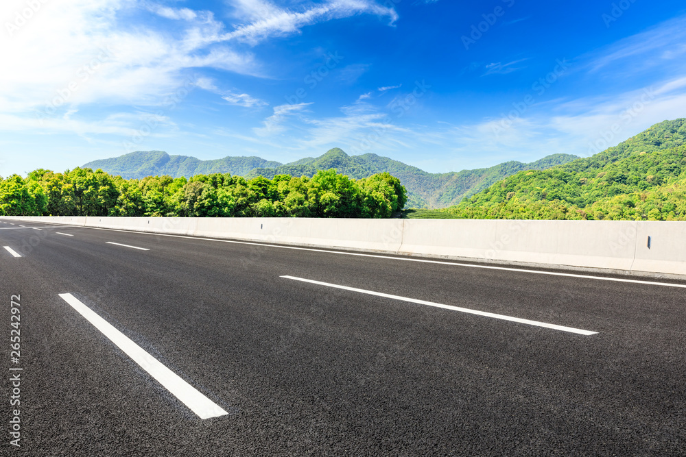 Fototapeta premium Country road and green mountains natural landscape under the blue sky
