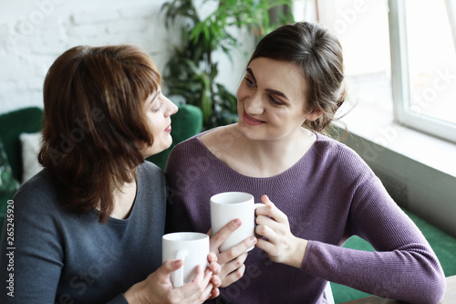 Beautiful mature mother and her adult daughter are drinking coffee 