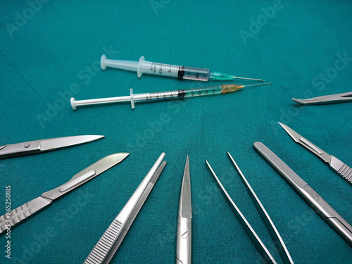 Surgical instrument with liquid parenteral products in syringe on surgical green drape fabric.