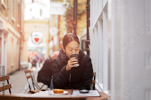 Beautiful asian woman drinking coffee with cake on table.