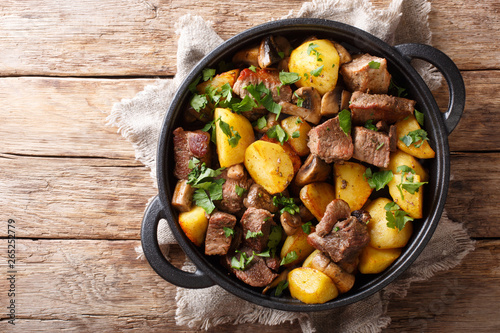 Traditional fried potatoes with pork and mushrooms close-up in a pan. horizontal top view