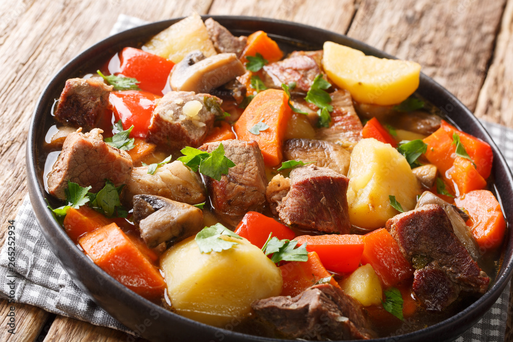 Pork gravy with mushrooms and vegetables close-up on a plate. horizontal