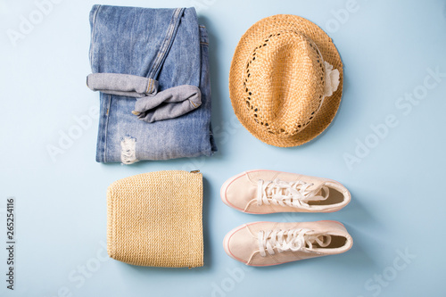 Outfit of casual woman. Collage on blue with jeans overalls, sneakers, handbag, wicker hat,