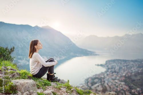 Child girl sitting with closed eyes above the mountain valley in a light of sunrise