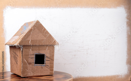 Handmade cardboard house on dirty white textured background.