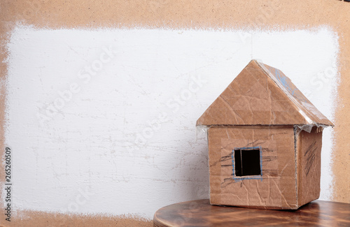 Handmade cardboard house on dirty white textured background.