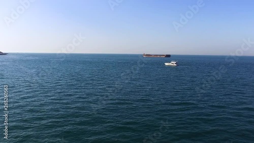 Aerial view of beautiful seascape with white yacht and dark barge on blue sky background. Stock. Beautiful calm sea in a sunny day with two floating vessels. photo