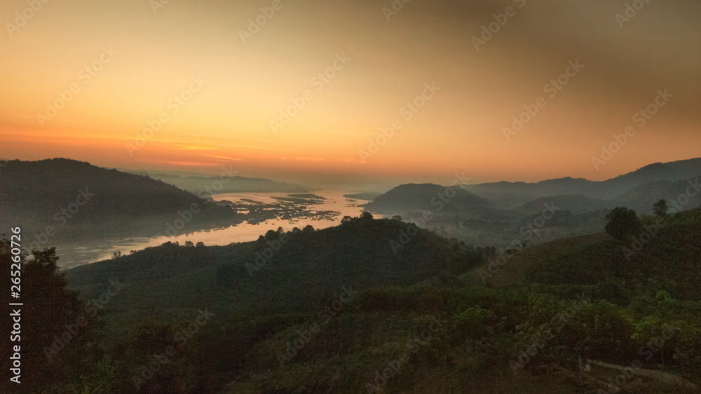 sunrise at Phu Huay Esan View Point, view of the hill around with sea of mist above Mekong river with soft red sun light in the sky background, Ban Muang, Sang Khom District, Nong Khai, Thailand.