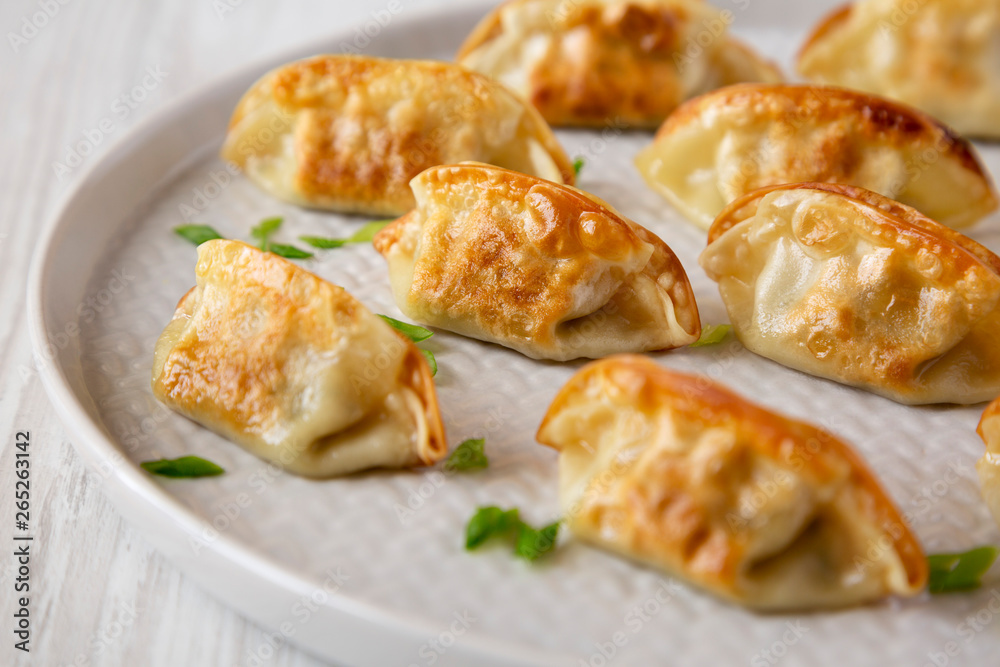 Homemade japanese gyoza on a plate over white wooden background, side view. Close-up. Homemade japanese gyoza on a plate over white wooden background, side view. Close-up.