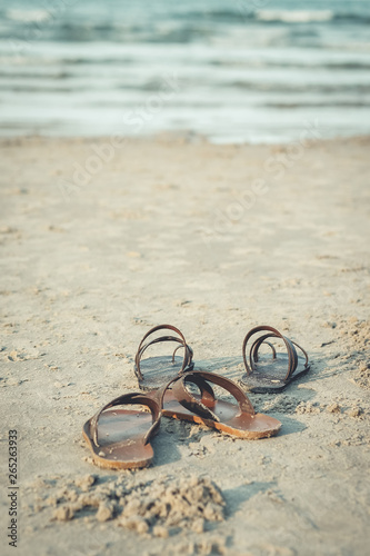 Sandals on the sand and the sea as a background.