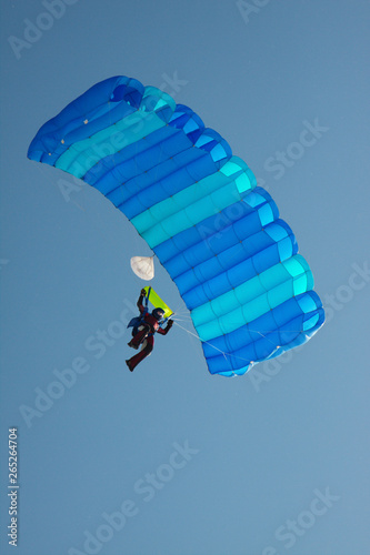 Skydiver with a parachute against the blue sky close-up.