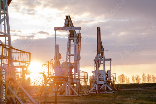 Oil well at sunset. Oil production by a rocker at sunset. Rocking machine for oil