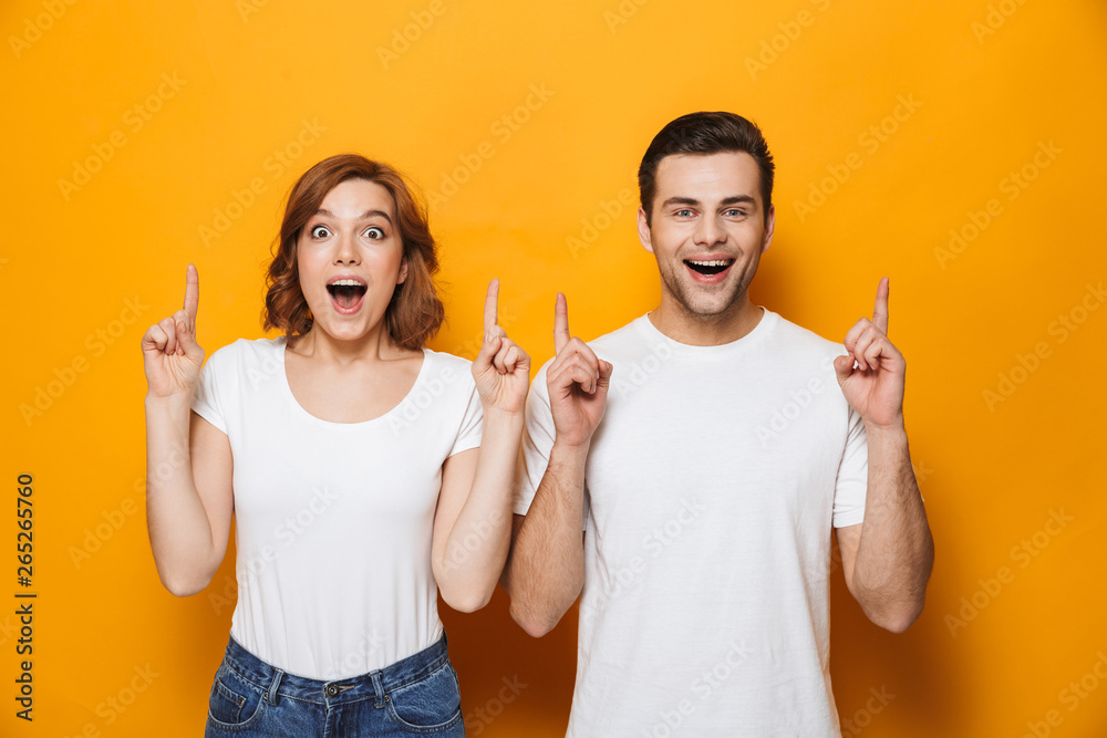 Excited beautiful couple wearing white t-shirts standing - obrazy, fototapety, plakaty 