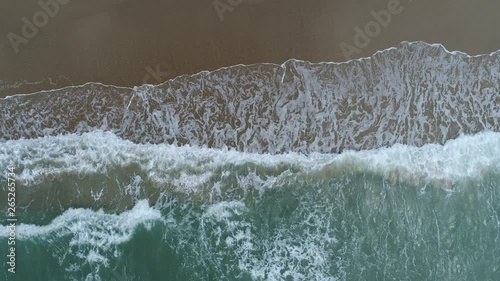 Aerial drone footage of ocean waves reaching shore. Beach on aerial drone top view.