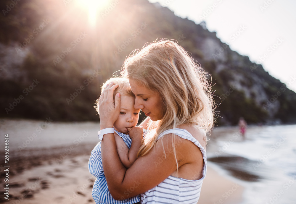 Young mother with a toddler girl on beach on summer holiday at sunset. Young mother with a toddler girl on beach on summer holiday at sunset.