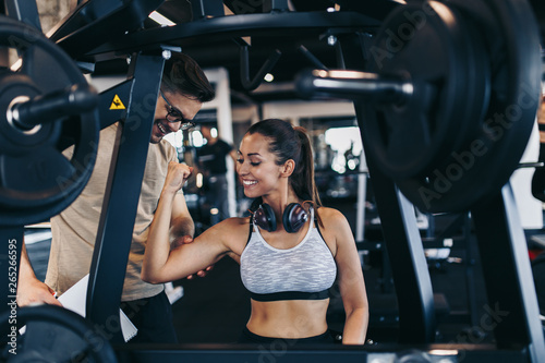 Young fit and attractive woman working out in modern gym together with her personal fitness instructor or coach.