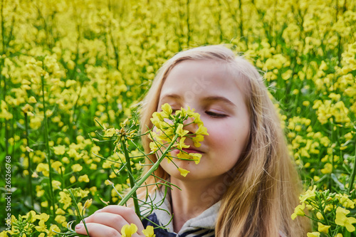 Closeup young girl happy on a sunny day in a rapeseed field  mustard with lots of yellow flowers