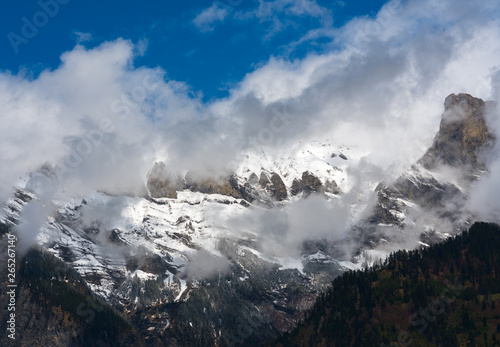 snowy and foggy mountain wilderness under a clearing blue sky