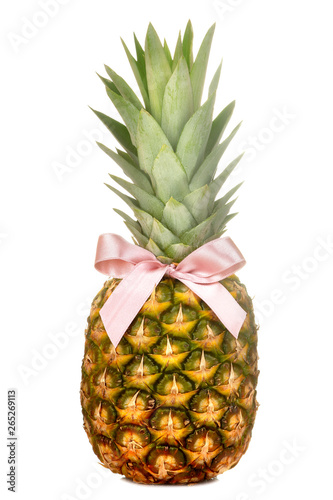 Large fresh ripe fruit pineapple with a pink bow on a white isolated background. summer fruit
