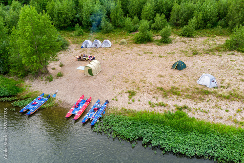Camping tents on the beach. Tourists rafting on the river on a halt