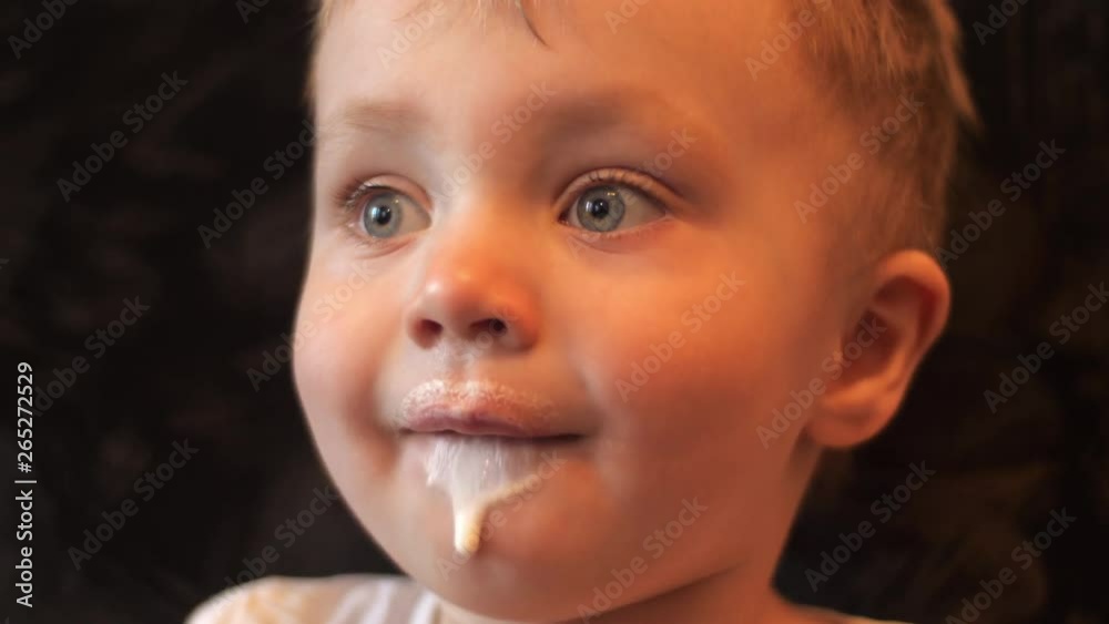 close-up portrait of a little kid who eating a white vanilla ice cream and his face smeared with it in slow motion 4K video. close-up portrait of a little kid who eating a white vanilla ice cream and his face smeared with it in slow motion 4K video.