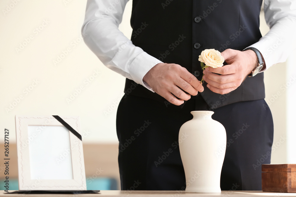 Man with mortuary urn and flower at funeral - obrazy, fototapety, plakaty 