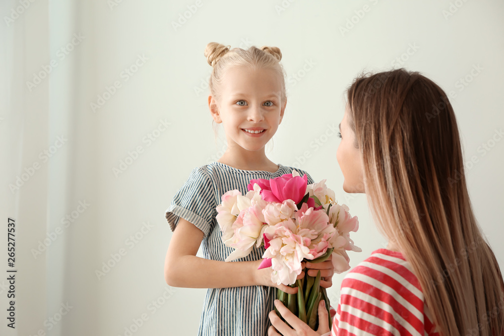 Little girl greeting her mother with bouquet of tulips at home Little girl greeting her mother with bouquet of tulips at home