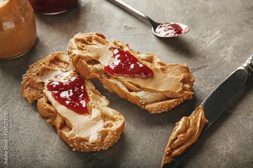 Toasted bread with tasty peanut butter and jam on grunge background