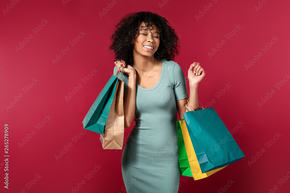 Happy African-American woman with shopping bags on color background Happy African-American woman with shopping bags on color background