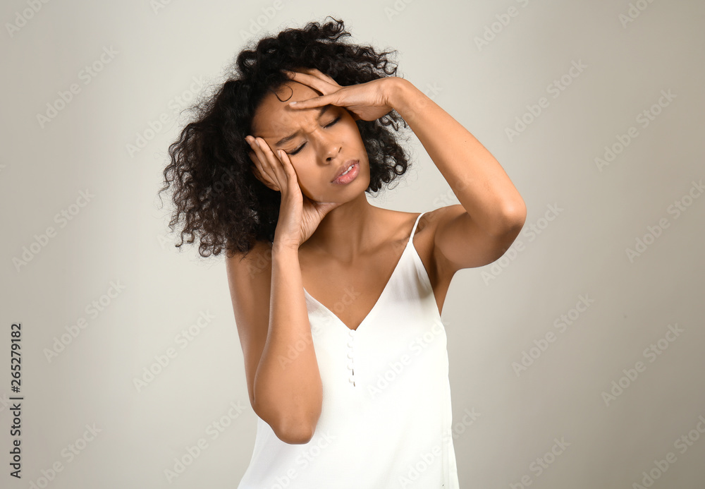 Fototapeta premium Stressed African-American woman on grey background