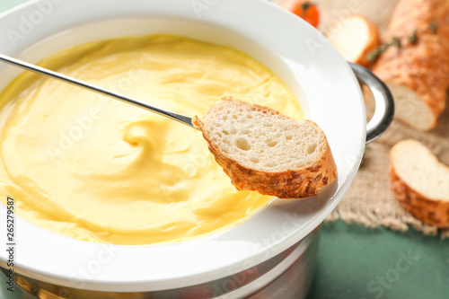 Dipping of bread into cheese fondue, closeup