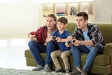 Gay couple with adopted child playing video game at home