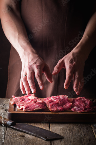 Fototapeta Naklejka Na Ścianę i Meble -  Man cooking meat steaks on kitchen. Chef salt and pepper meat on wooden background