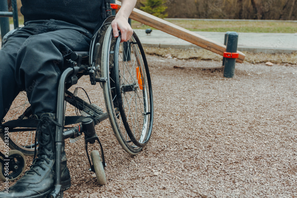 Obraz premium Close-up of male hand on wheel of wheelchair during walk in park